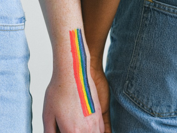 people holding hands with rainbow flag painted on their arm