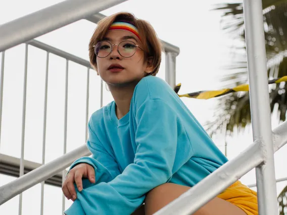 person sitting on outdoor stairs wearing a rainbow headband