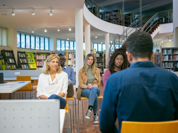 a small group of students listening to a presentation in a library
