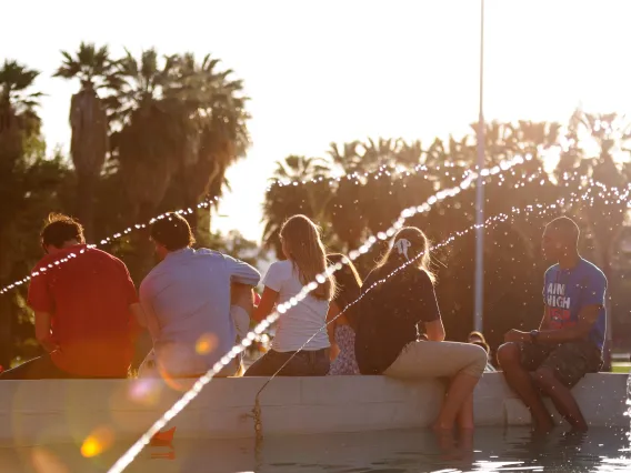 group of students sitting by a fountain and talking