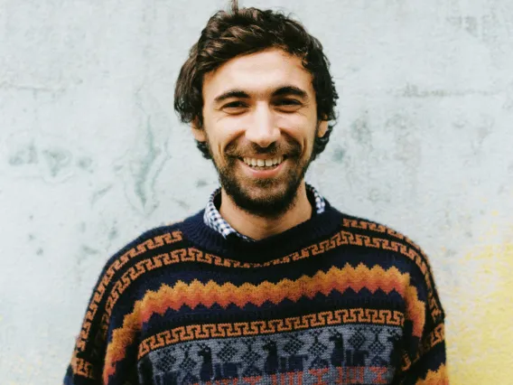 person standing in front of a concrete wall smiling