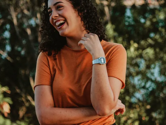 person looking to the side smiling with trees in the background