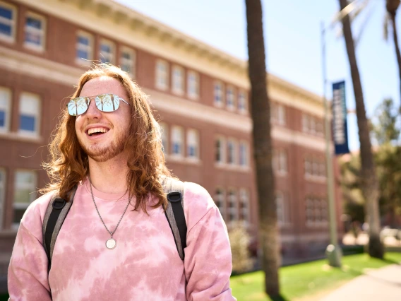 person standing outdoors wearing sunglasses and smiling