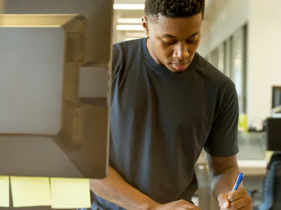 person using a computer and taking notes