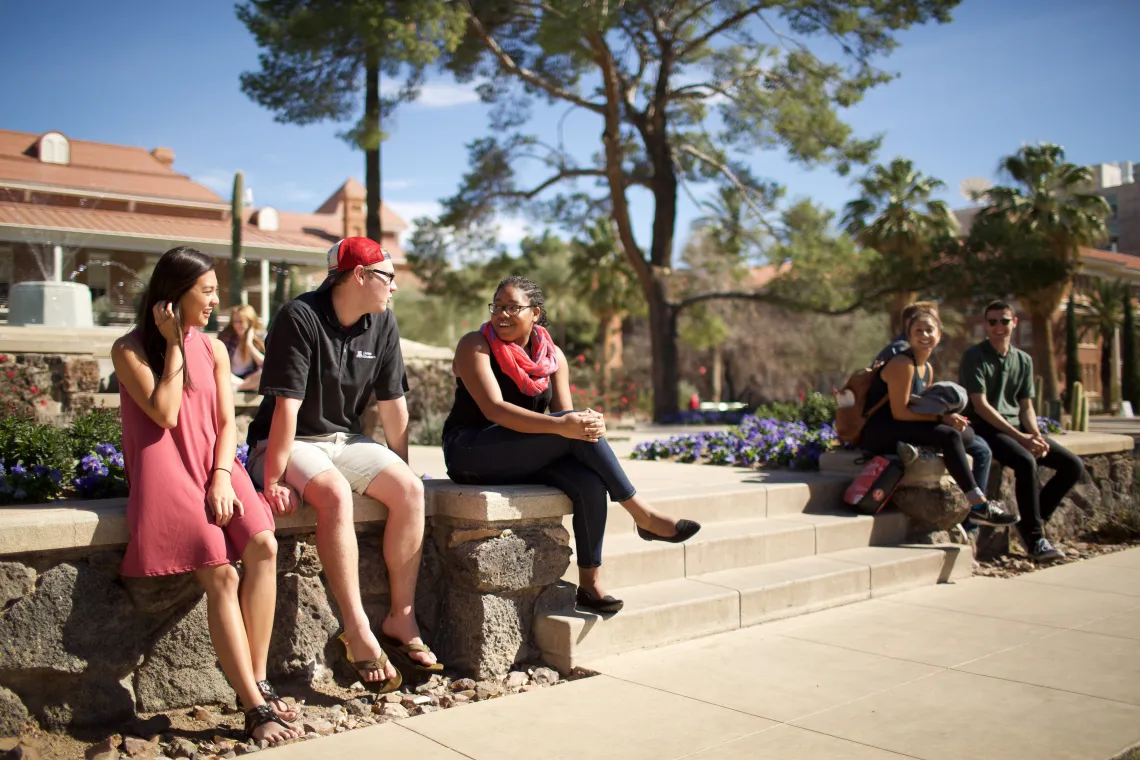 group of people sitting on a bench in front of a fountain