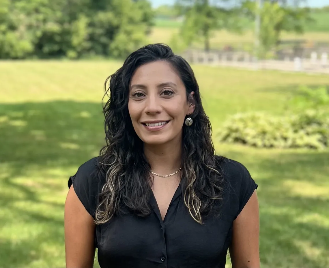 headshot of a person standing outside with grass and trees in the background