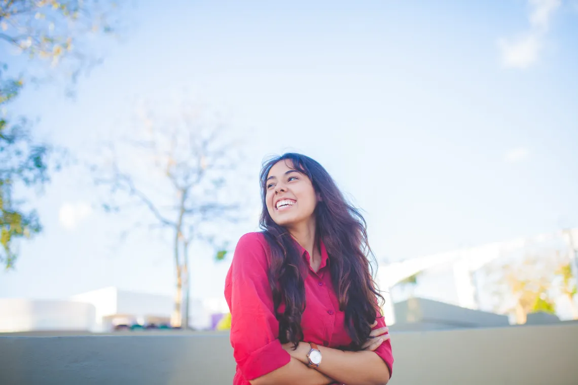 person seen from the waist up smiling with a blue sky in the background