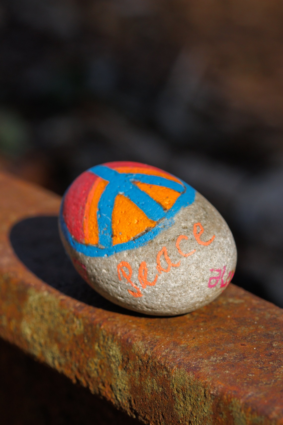 stone painted with a peace sign and text that reads peace