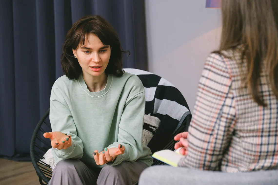 person sitting in a chair talking to someone at the edge of the frame