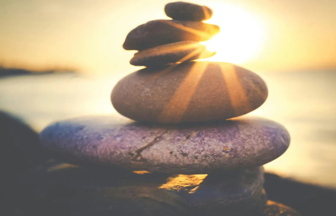 stack of stones with the ocean and sunset visible in the background