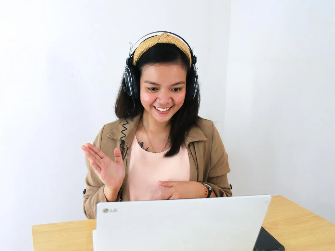 woman smiling and waving at a laptop