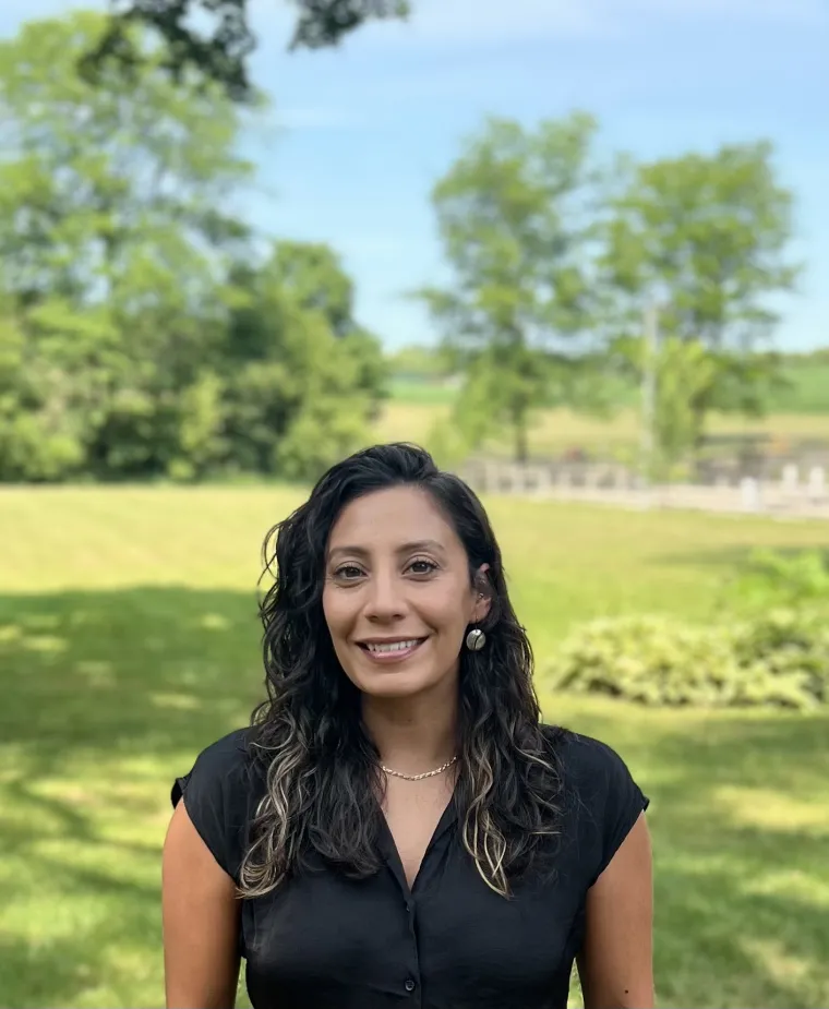 headshot of a person standing outside with grass and trees in the background