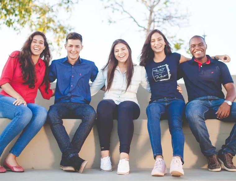 Group of 5 students sitting together and smiling