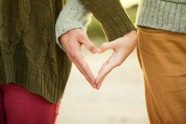 two people holding their hand together in the shape of a heart